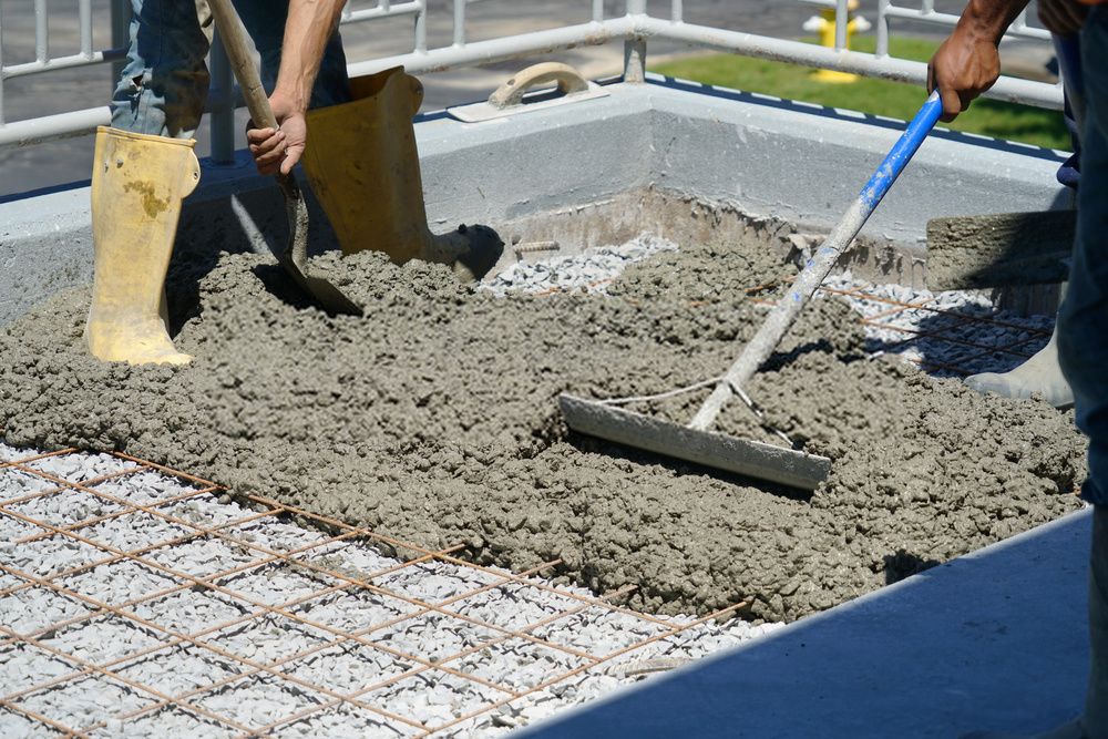 contractors spreading the concrete mixture around the frame
